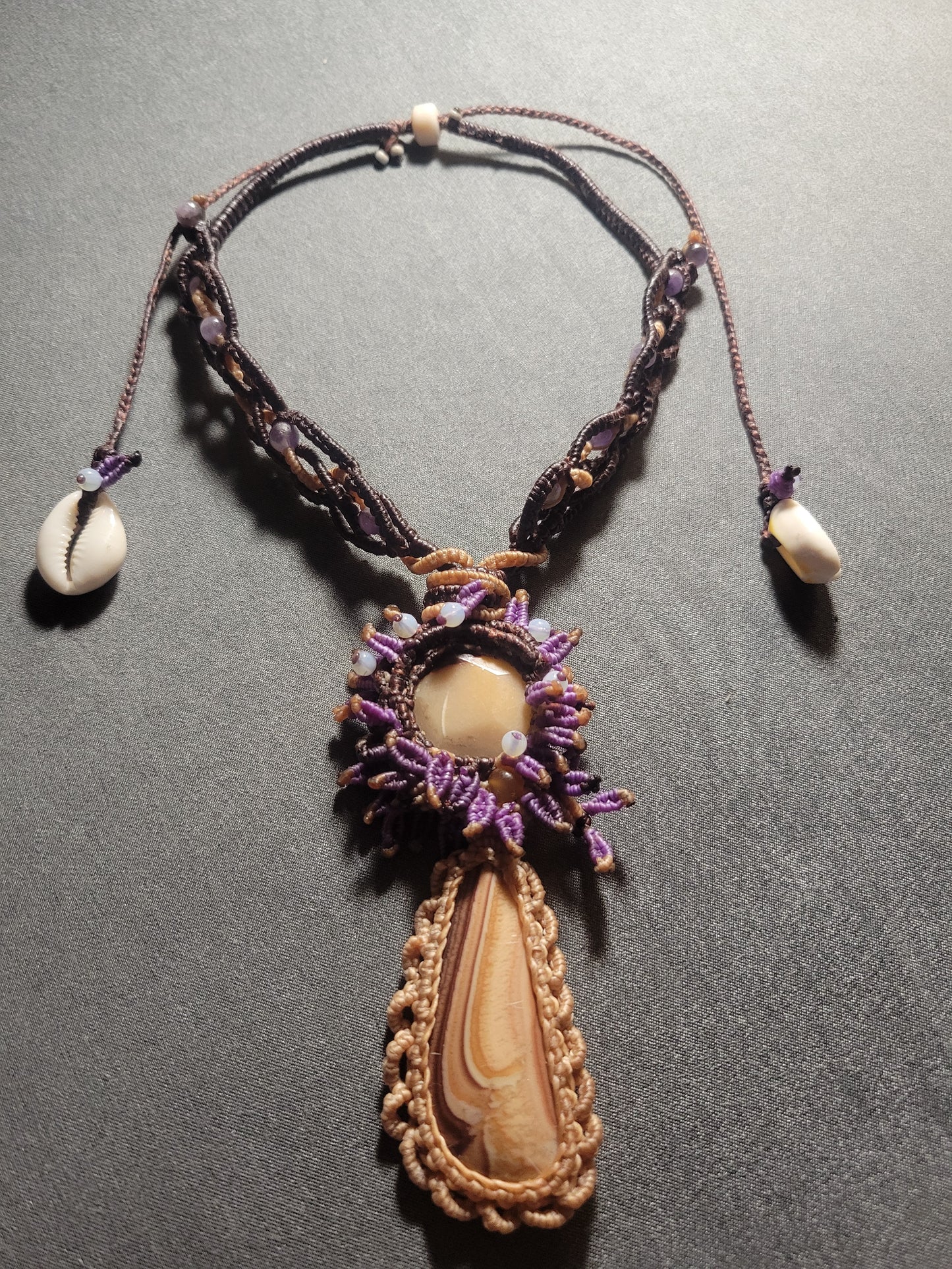 Jasper Jewelry – Polychrome Stone & Shiva’s Eye Shell Choker with intricate micromacramé and purple leaf patterns.