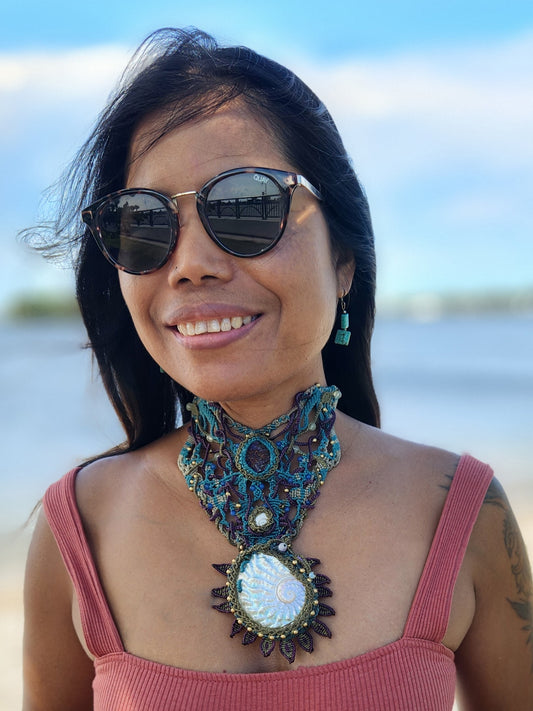 Shell Pendant – Ocean Priestess Abalone Statement Choker worn by a woman on the beach, featuring intricate micromacramé design.