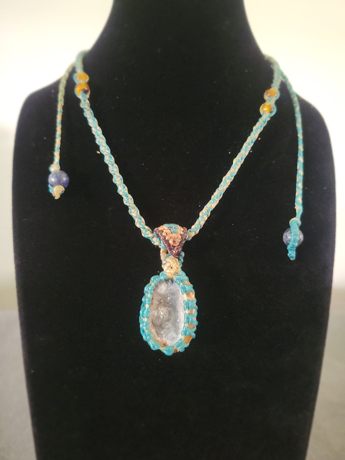 Agate Necklace – 'Shining with Grace' Natural geode pendant on a display stand with colorful accents.