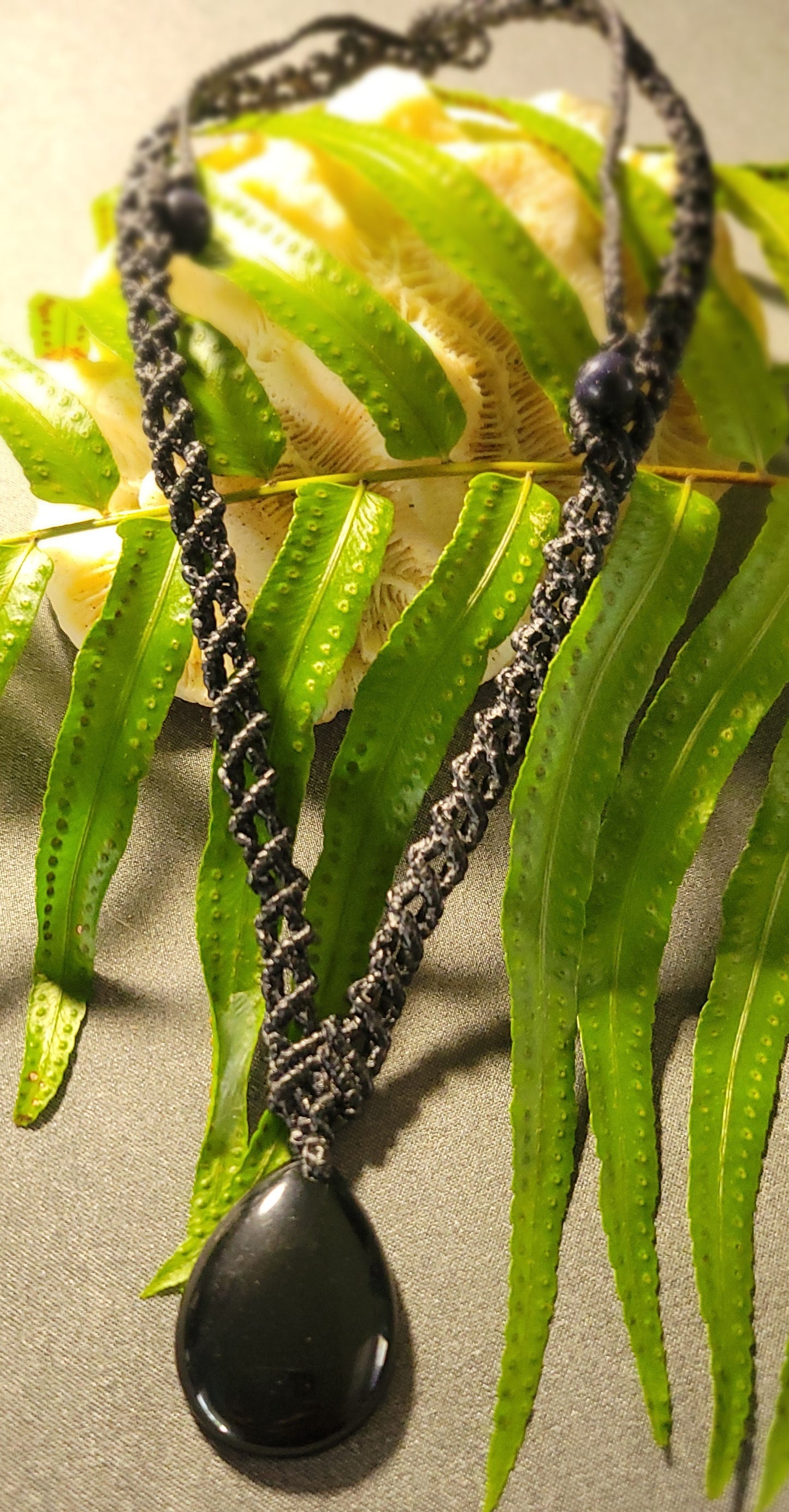 Black Jade – Boho Wave Pendant Necklace with Spiral Braid on leaf background, featuring natural black jade stone and macramé cord.