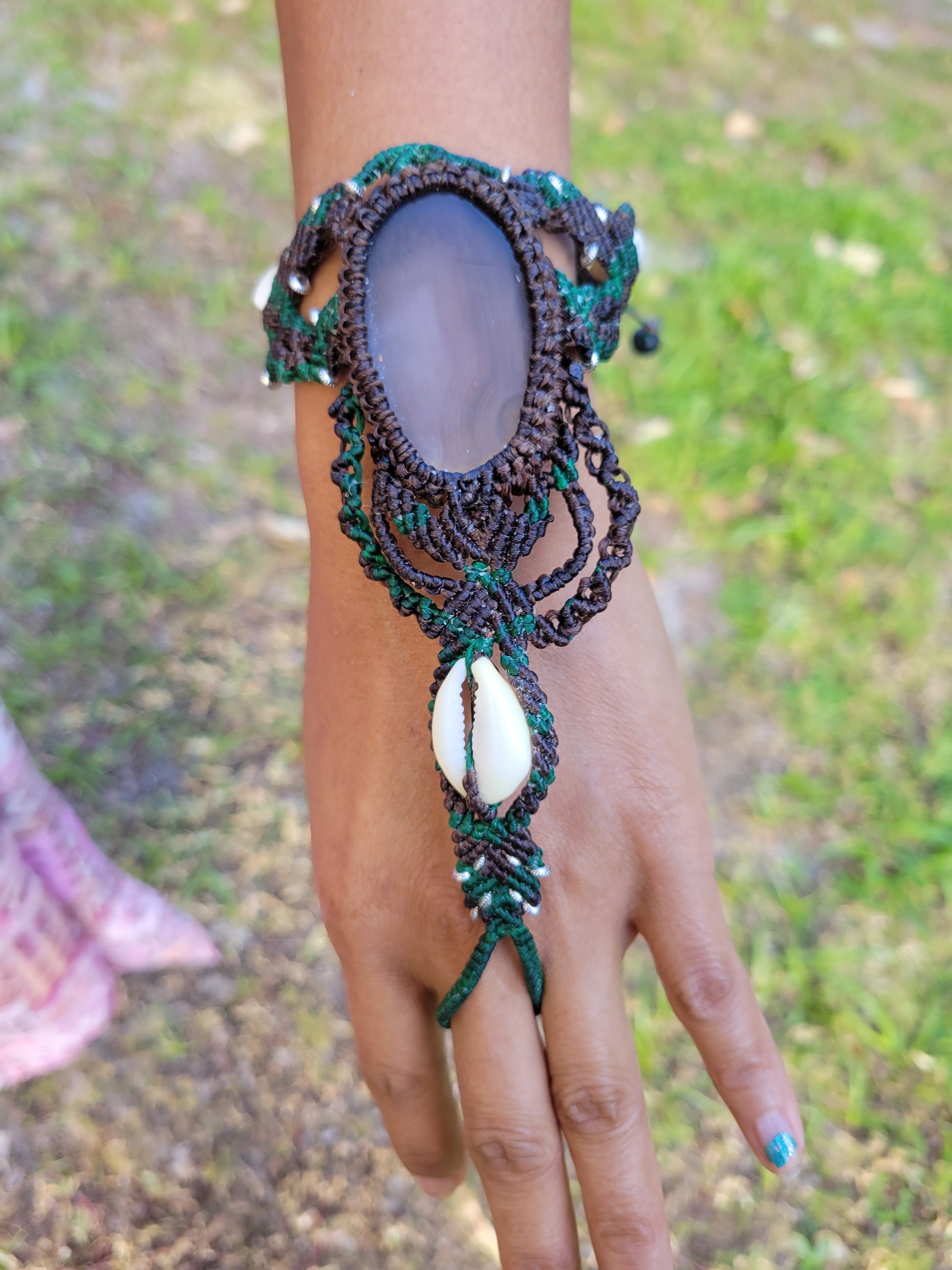 Belly Dancer Bracelet featuring natural agate slice and cowrie shell accents, worn on a hand outdoors.