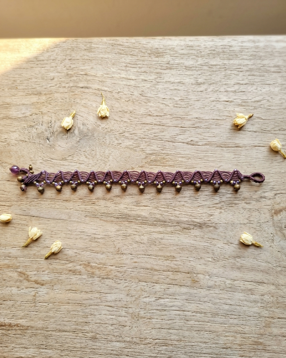 Boho Anklets – Handmade brass bell macramé anklet on a wooden surface with decorative flowers.