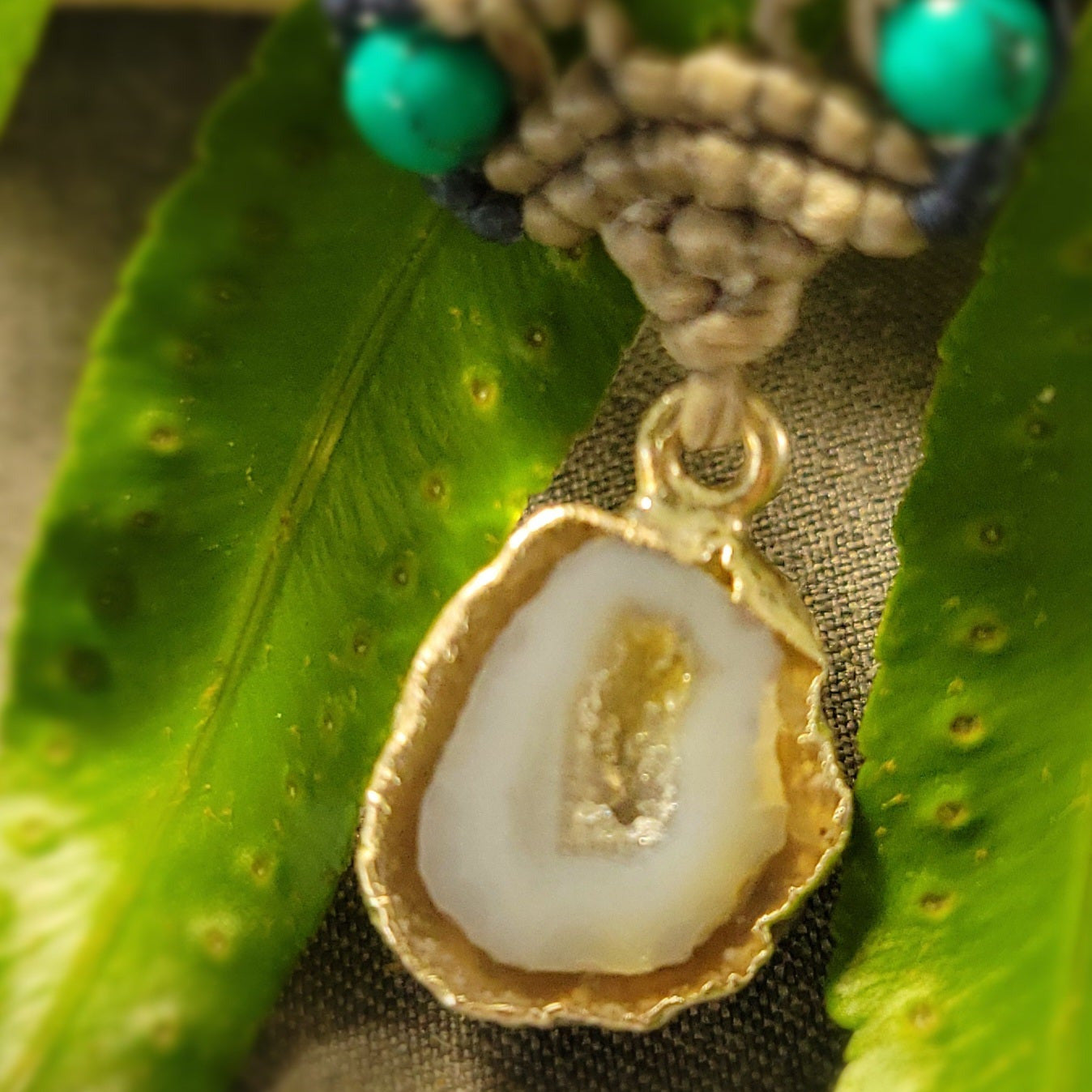 Agate Geode Necklace with natural agate slice and malachite accents on a green leafy background.
