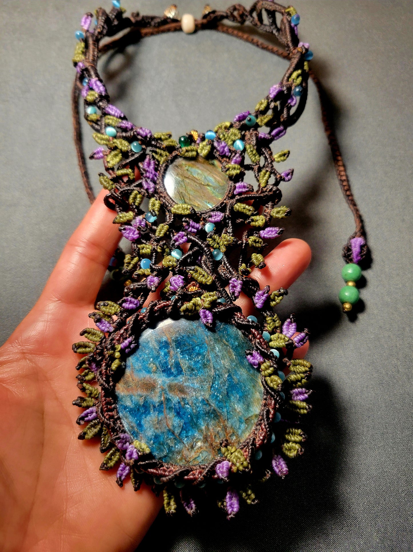 Apatite Pendant featuring large blue apatite stone and intricate micromacramé design with colorful leaf accents.