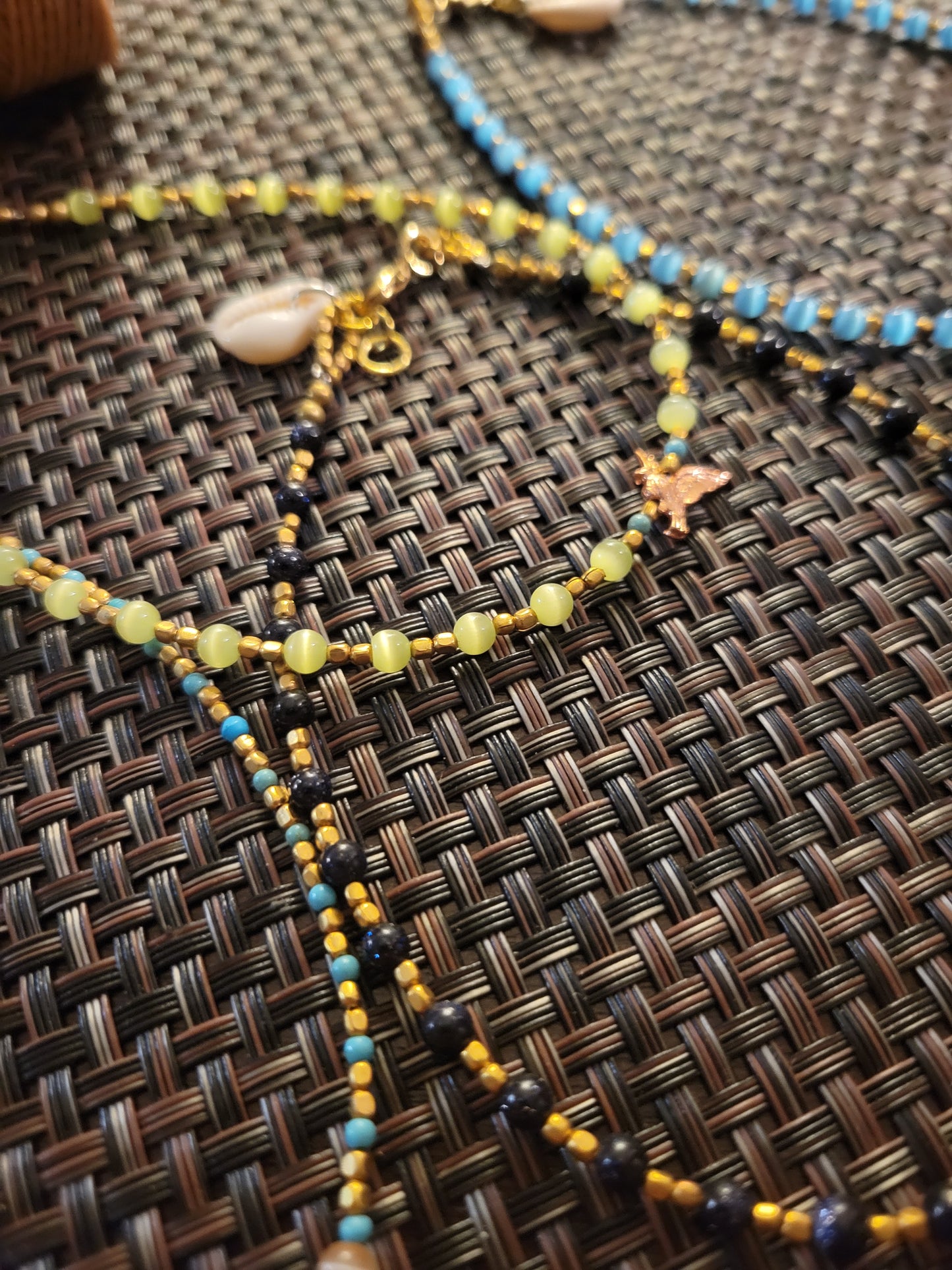 Boho Anklets – Beaded ocean charm anklets with colorful beads and shells on a textured background.