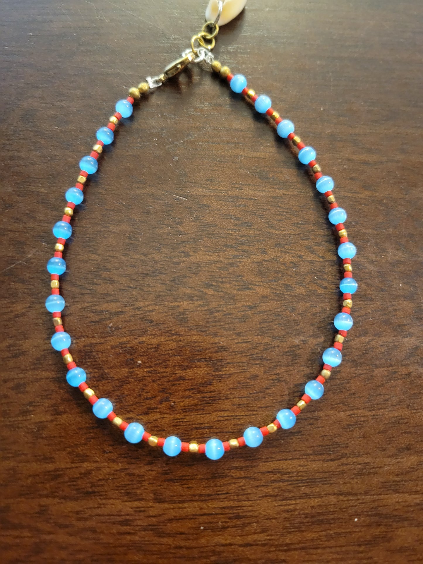 Boho Anklets – Beaded ocean charm anklet featuring blue and red beads with brass accents.