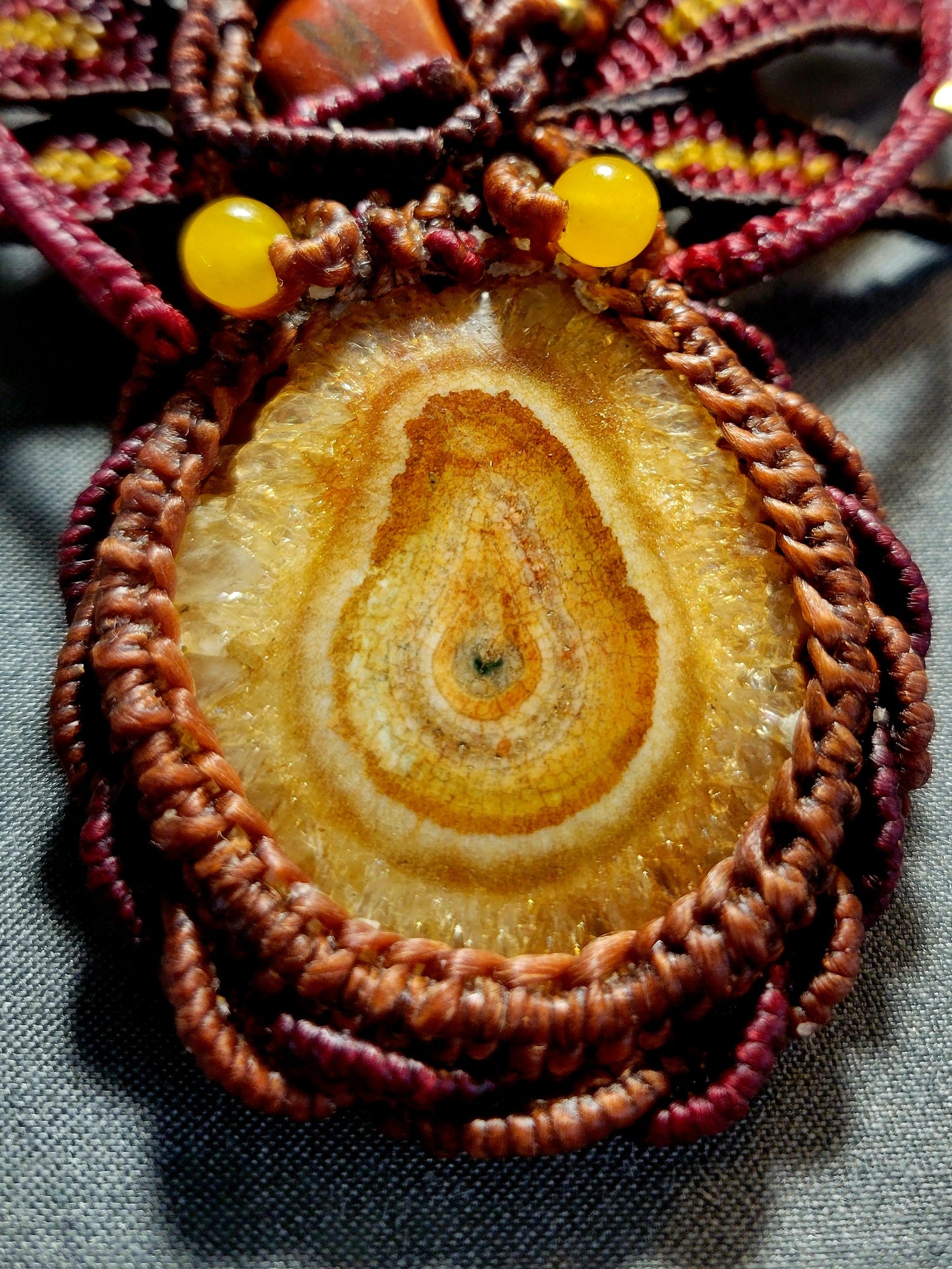 Close-up of an Agate Boho Necklace featuring a honey yellow agate stalactite slice and brown waxed cotton macramé.