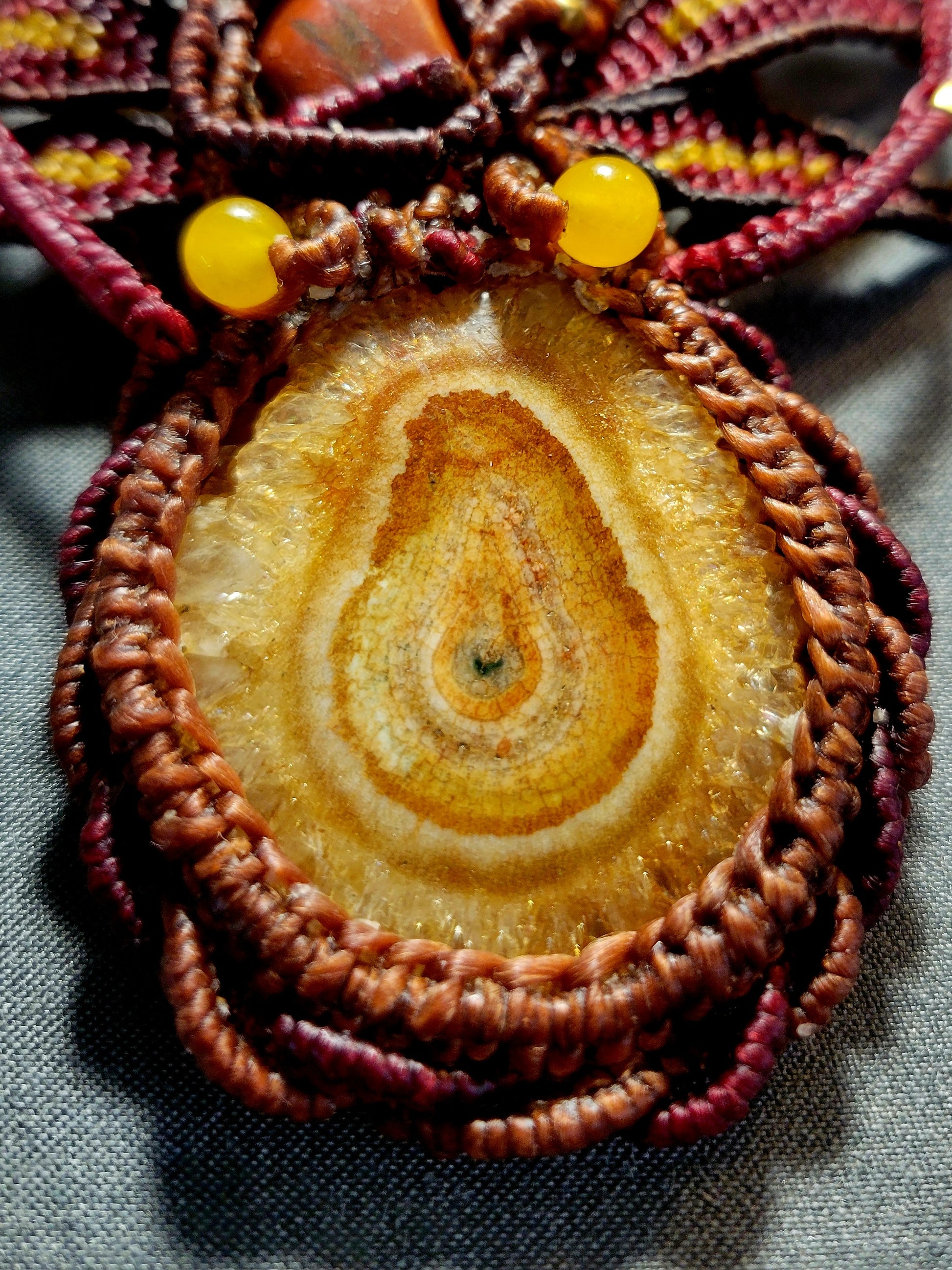 Close-up of an Agate Boho Necklace featuring a honey yellow agate stalactite slice and brown waxed cotton macramé.