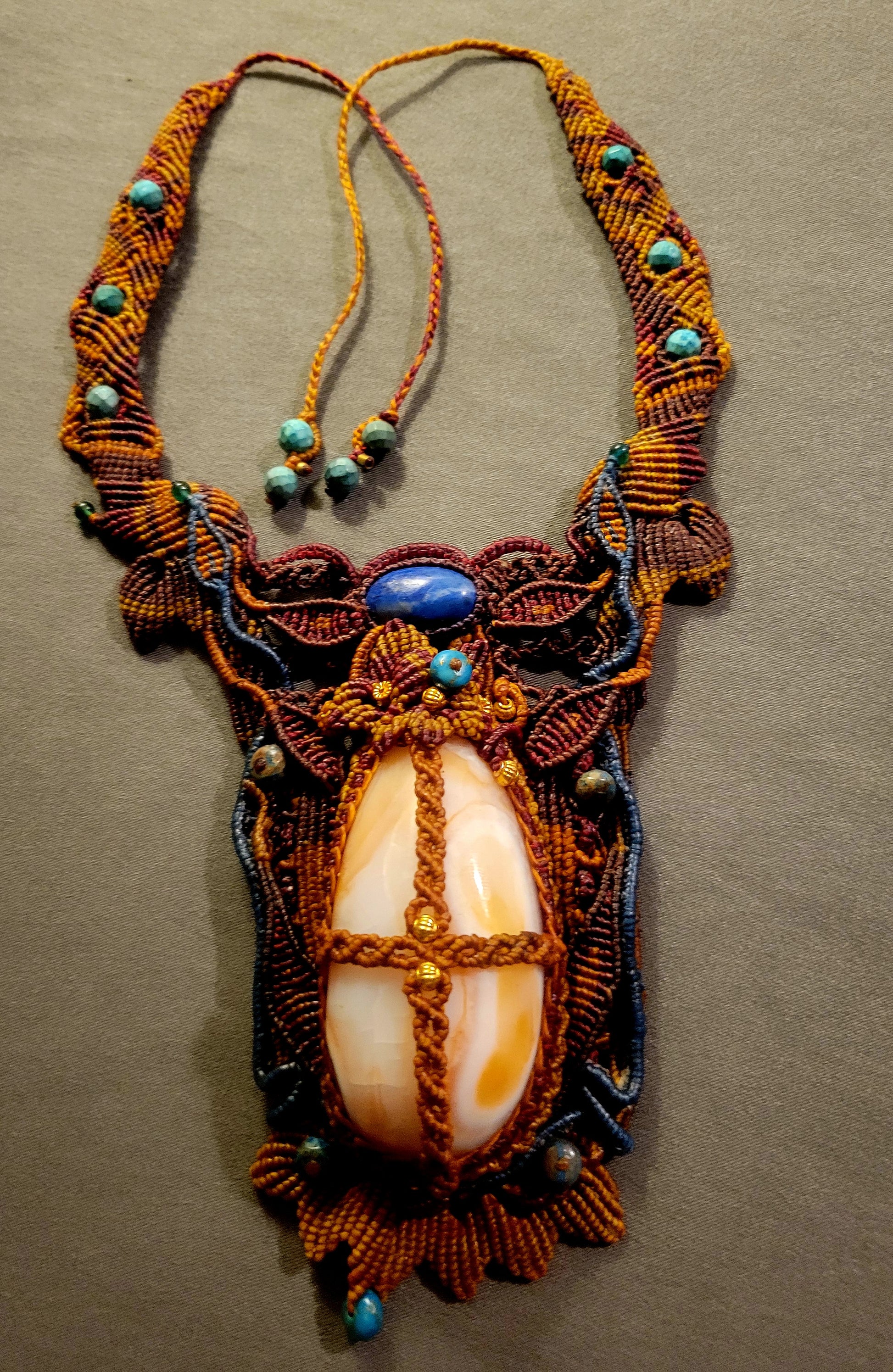 Carnelian Pendant featuring large pale carnelian agate stone and ornate micromacramé design with lapis lazuli accents.