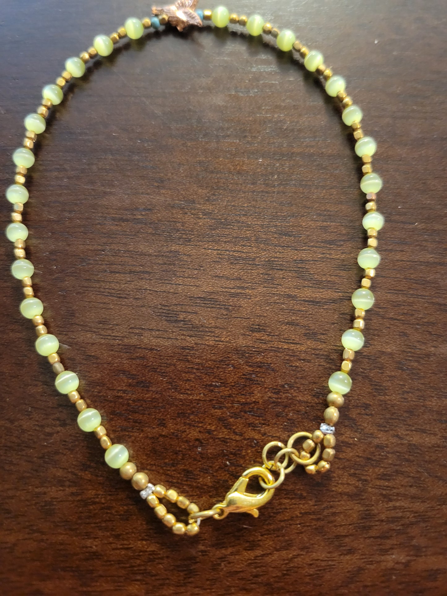 Boho Anklets – Beaded ocean charm anklet featuring yellow cat’s eye beads and gold accents.