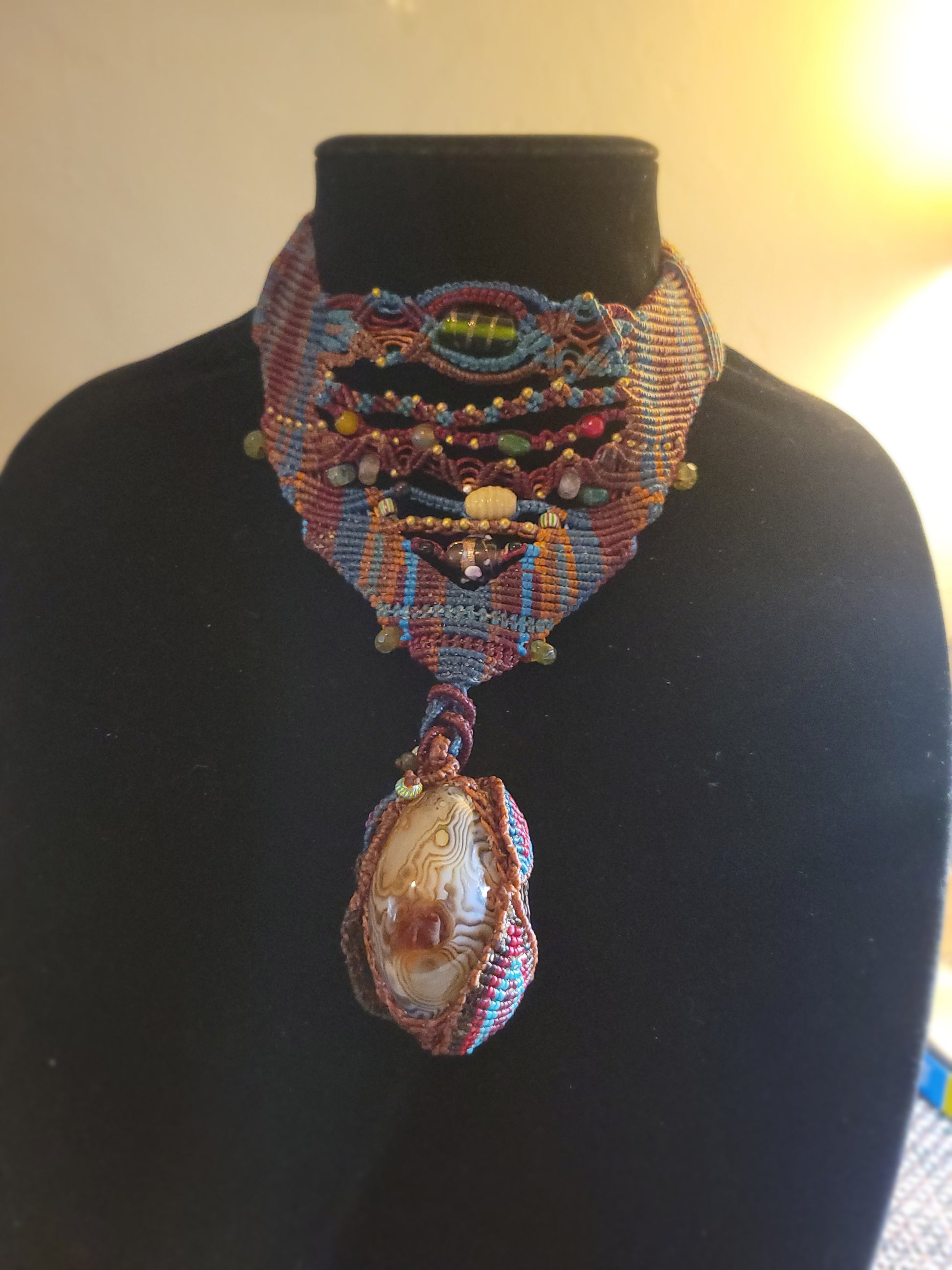 Botswana Agate Pendant showcasing intricate micromacramé design and natural stone accents in earthy tones.