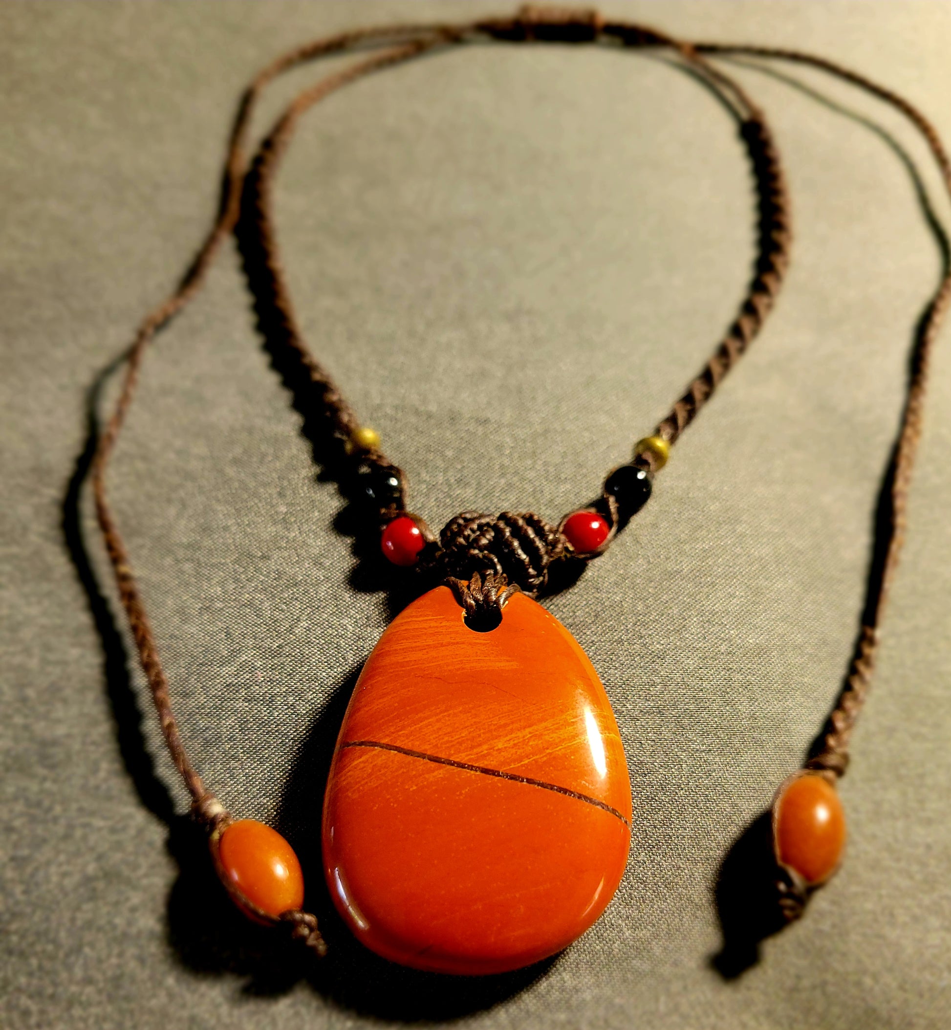 Jasper Healing Stone – Earthkeeper Red Jasper Pendant on a braided necklace, showcasing its natural beauty.