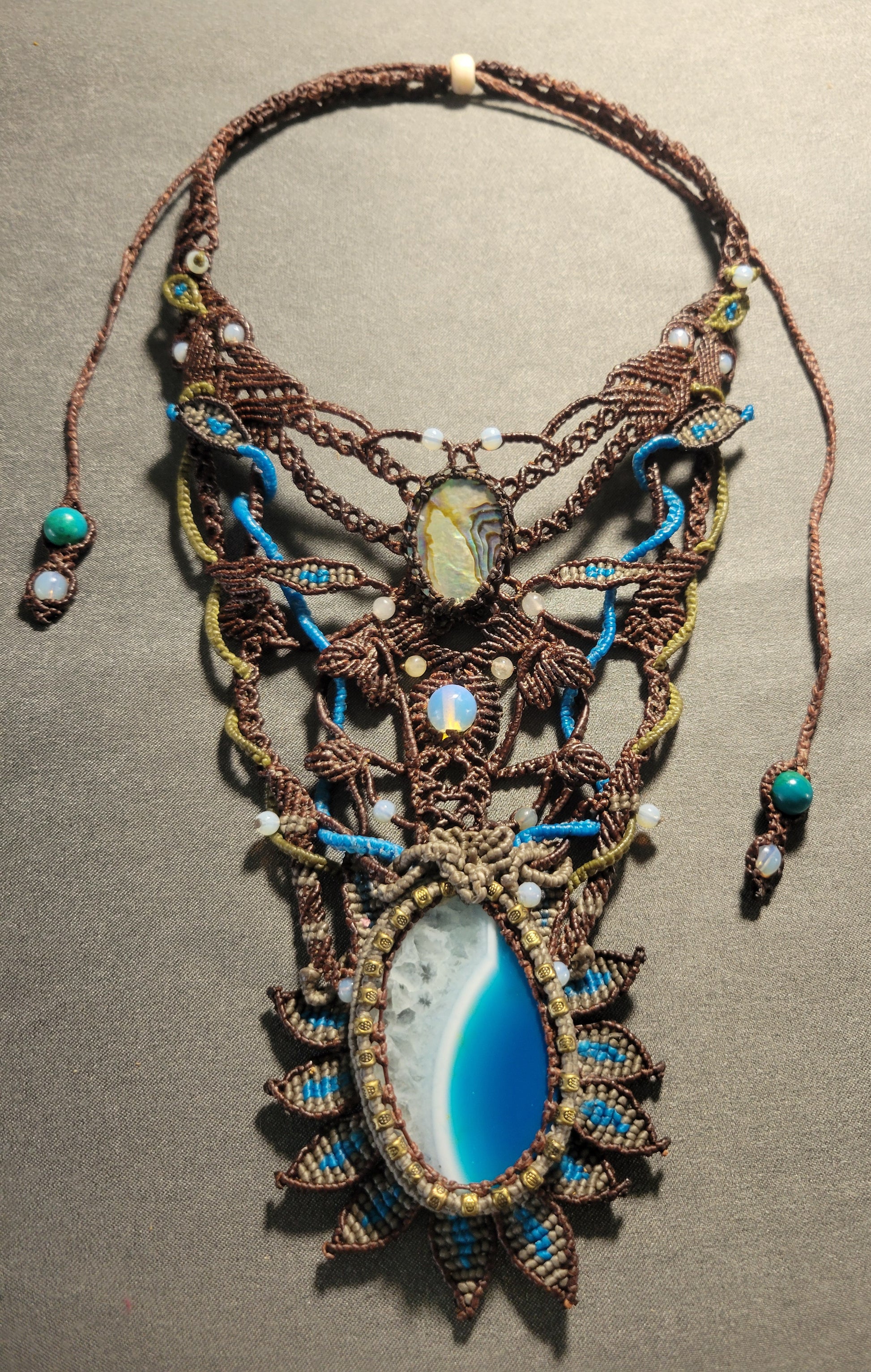 Agate Boho Necklace featuring an ocean wave agate slice and ornate micromacramé design with colorful accents.