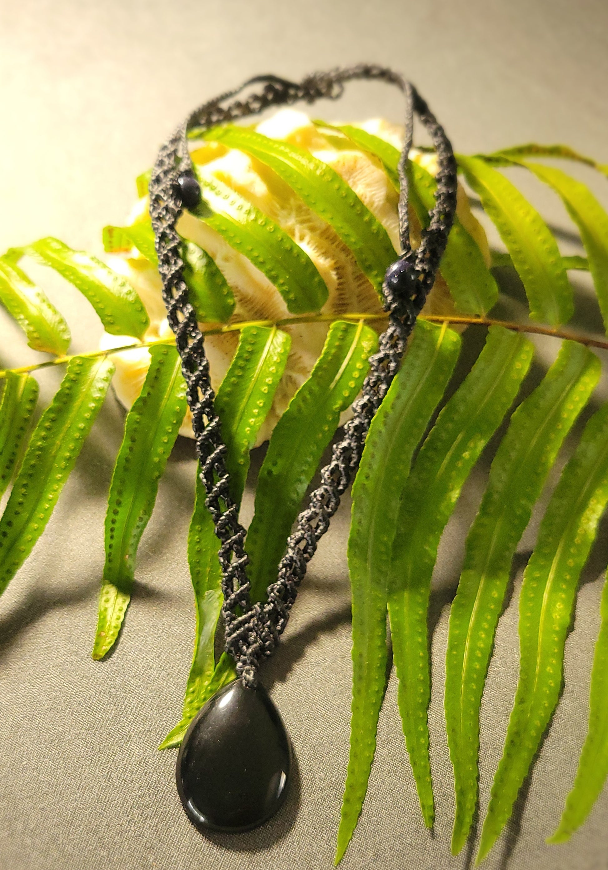 Black Jade – Boho Wave Pendant Necklace with Spiral Braid on fern background.