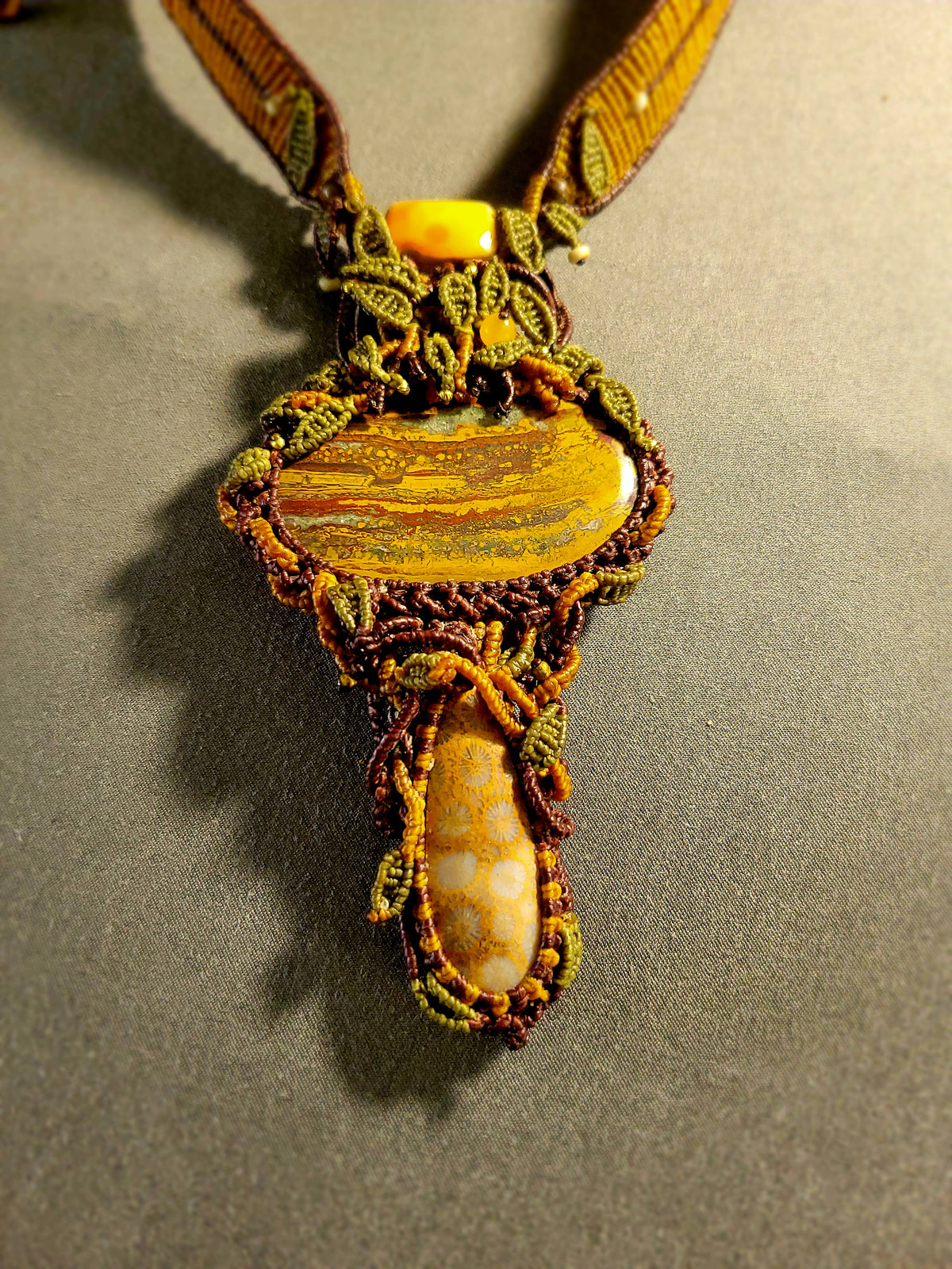 Tiger’s Eye Pendant featuring natural iron stone centerpiece and fossil coral with ornate micromacramé design.