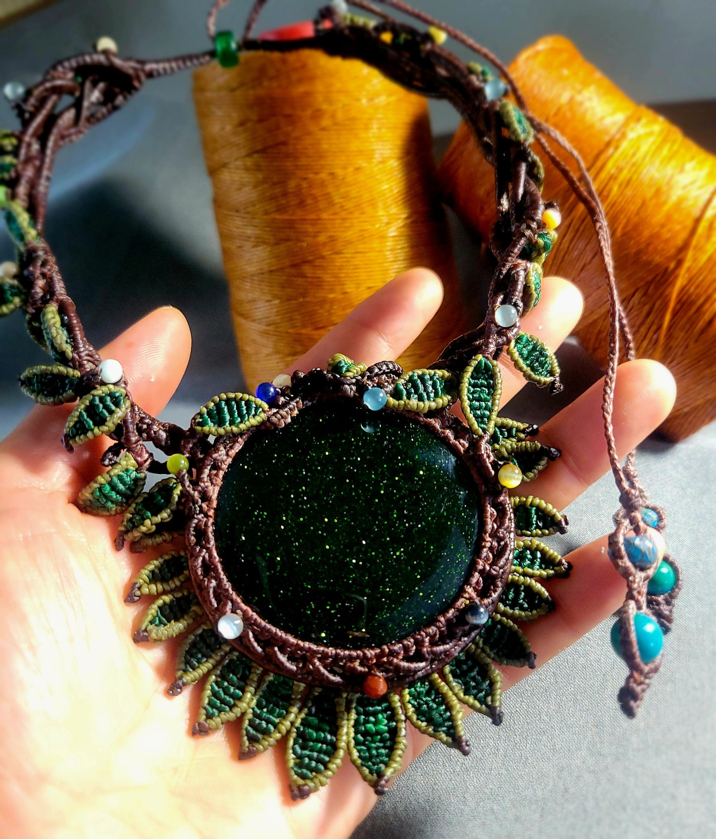 Sandstone Necklace featuring dark green sandstone pendant and micromacramé leaf design accents.