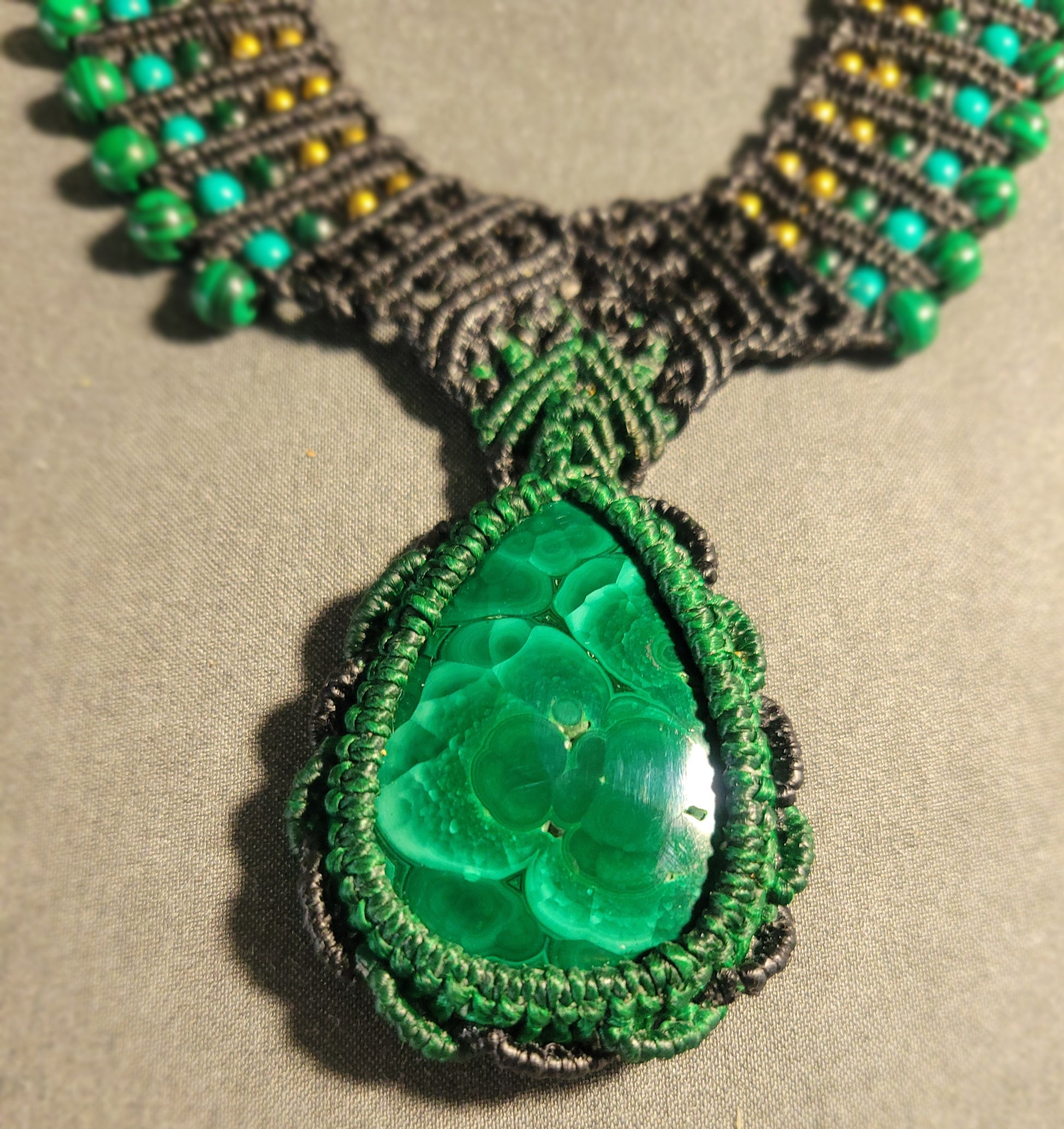 Malachite Pendant Necklace featuring a large green malachite stone and macramé choker design with beads.