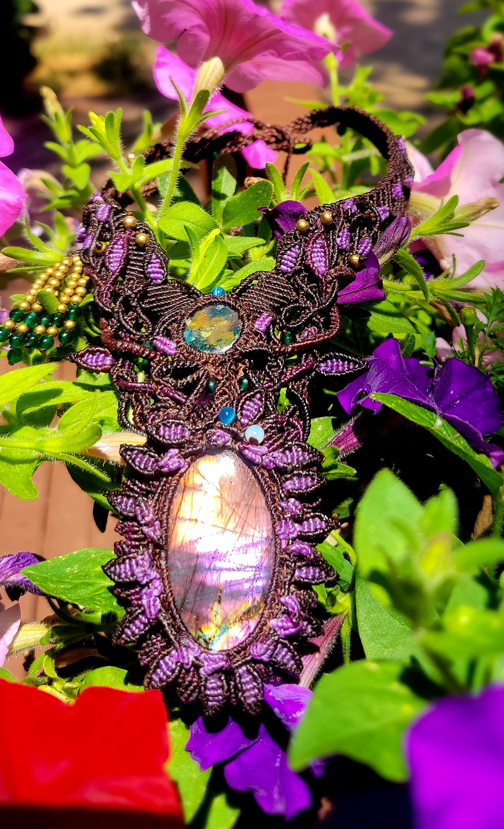 Labradorite Pendant Necklace showcasing large iridescent stone amidst colorful flowers and intricate micromacramé design.