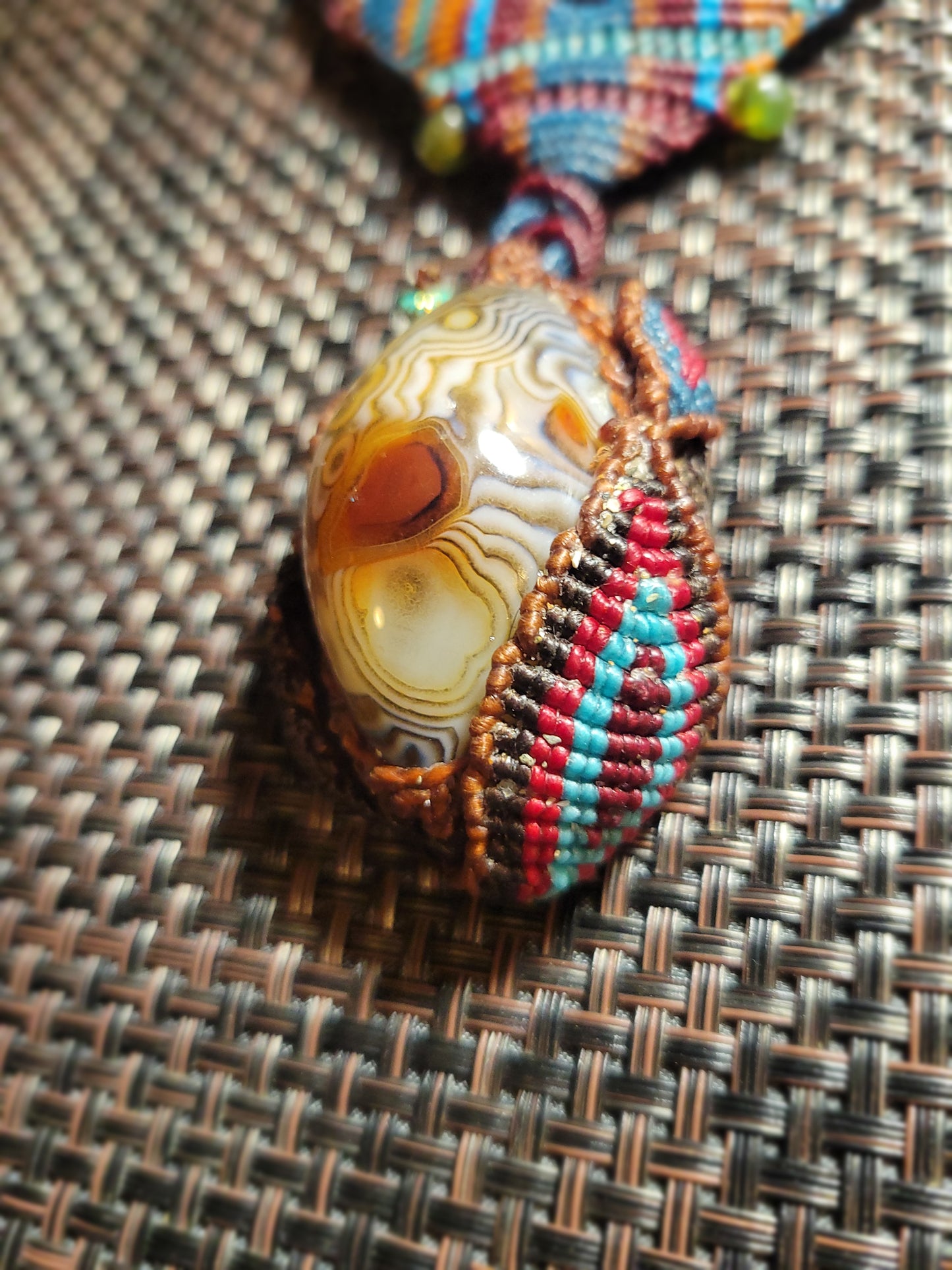 Botswana Agate Pendant featuring intricate micromacramé wrap and earthy colors in a tribal design.