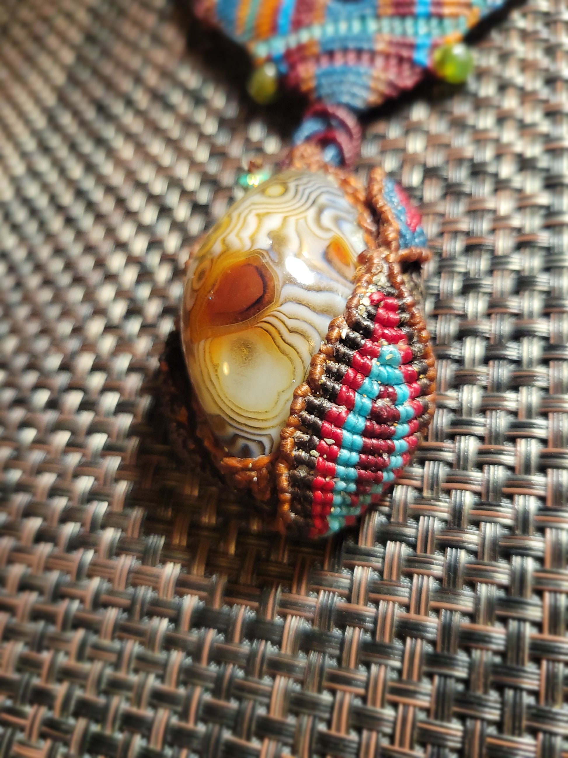 Botswana Agate Pendant featuring intricate micromacramé wrap and earthy colors in a tribal design.