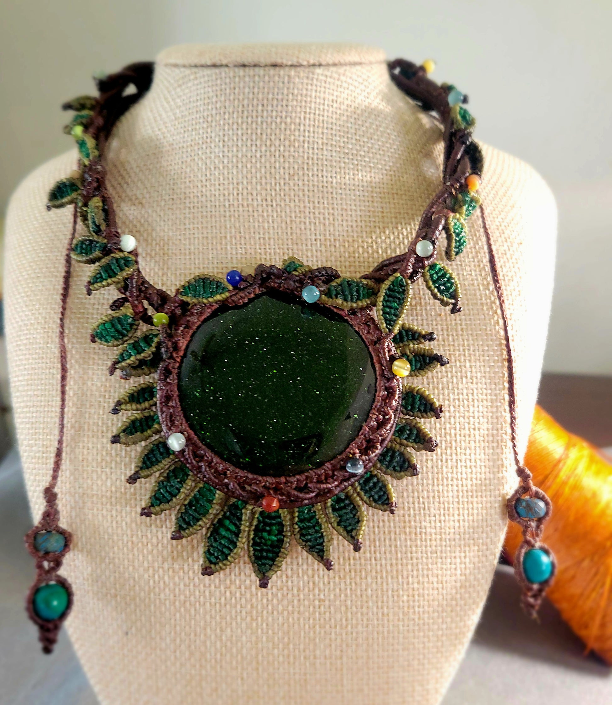 Sandstone Necklace showcasing a large dark green sandstone stone with micromacramé flower petal design and leaf motifs.