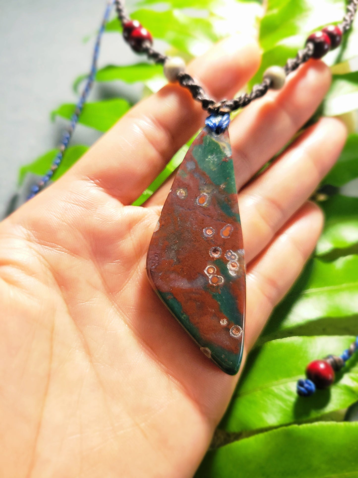 Bloodstone Pendant displayed in hand, showcasing distinctive red and green patterns on a minimalist macramé necklace.