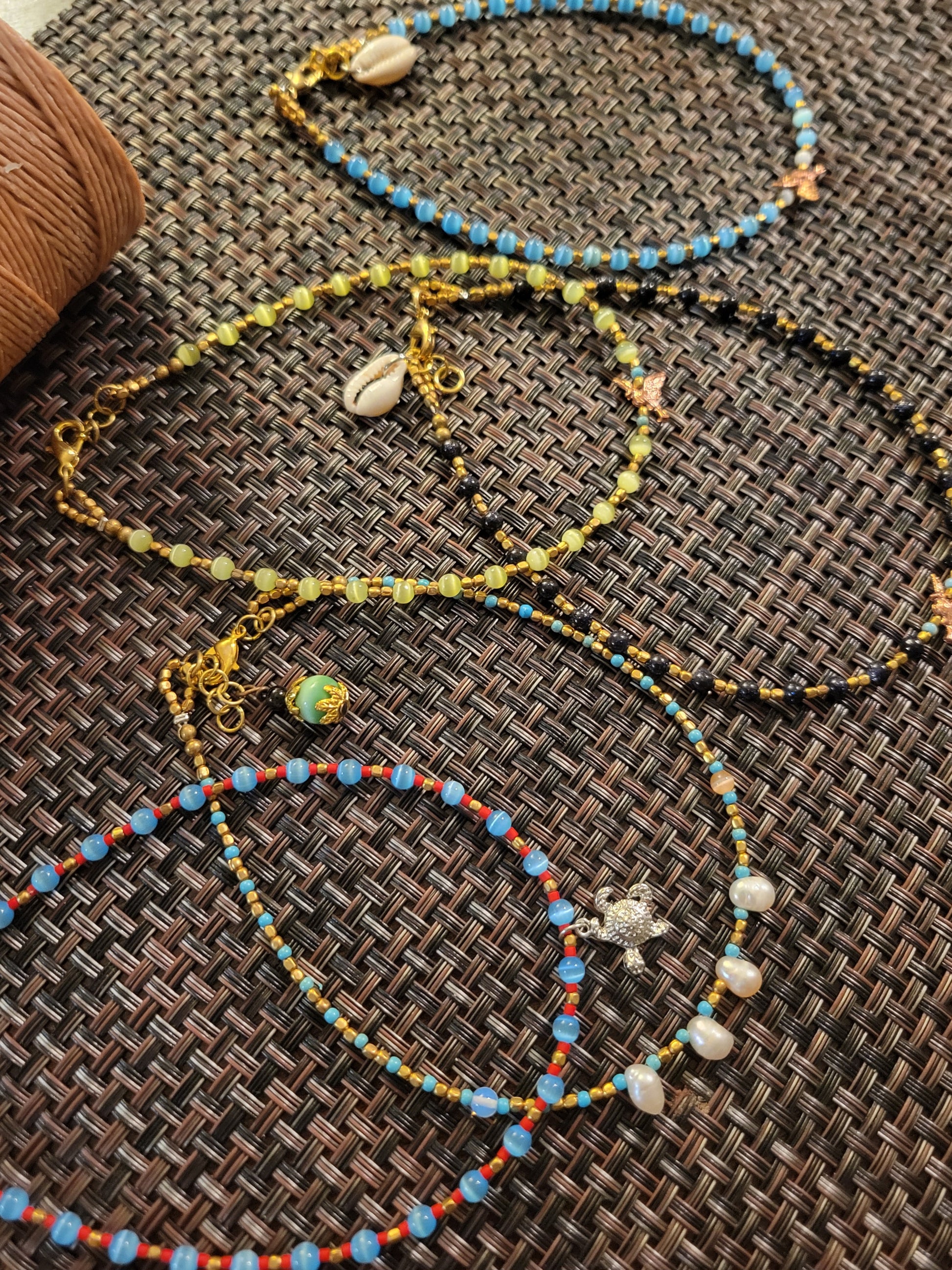 Boho Anklets showcasing beaded ocean charm designs with shells and vibrant colors on a textured surface.