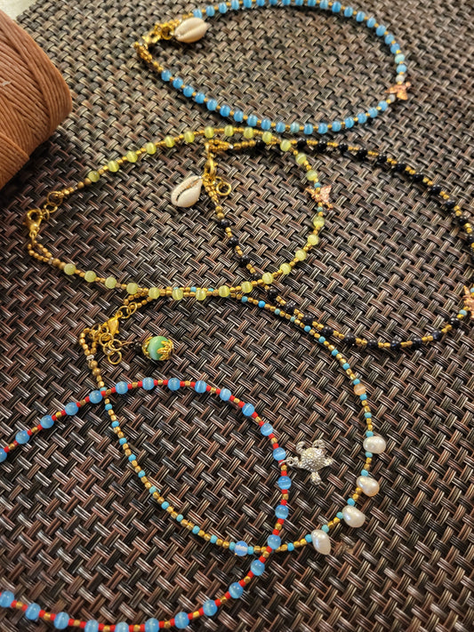 Boho Anklets showcasing beaded ocean charm designs with shells and vibrant colors on a textured surface.