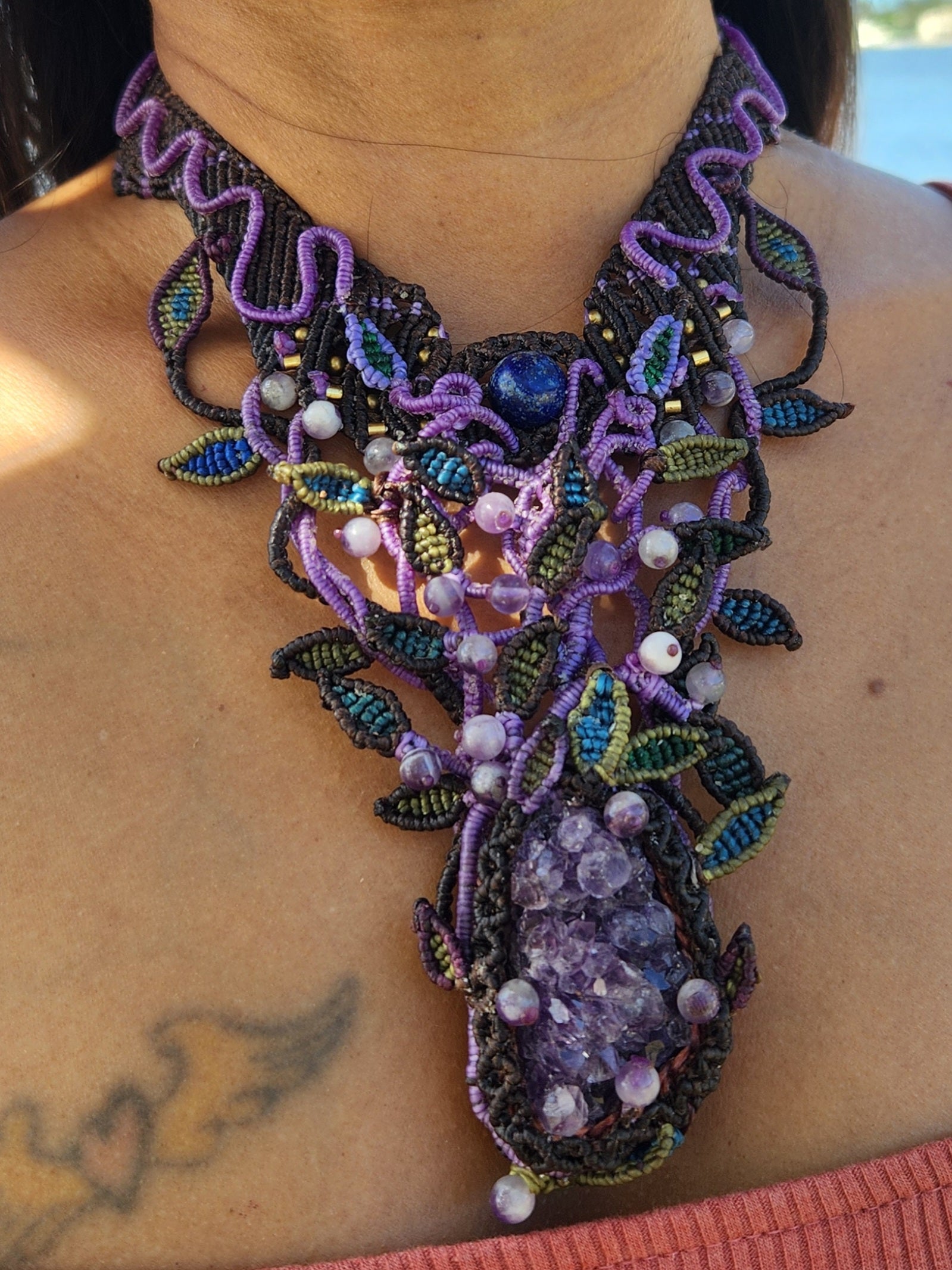 Amethyst Pendant featuring a large raw amethyst crystal with intricate micromacramé vine patterns and colorful beads.