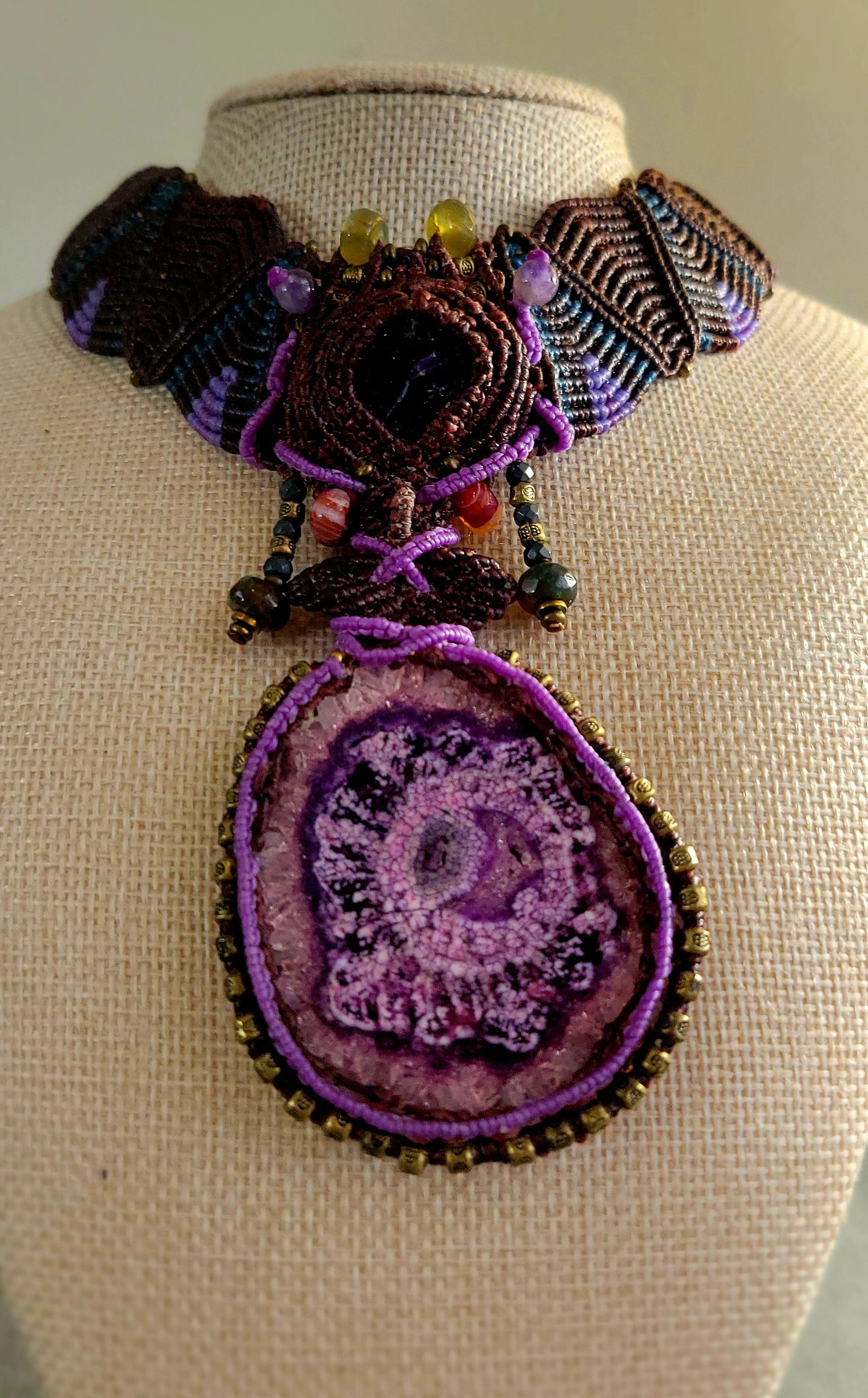 Agate Necklace featuring a large purple stalactite pendant, intricate micromacramé design, and antique brass details.