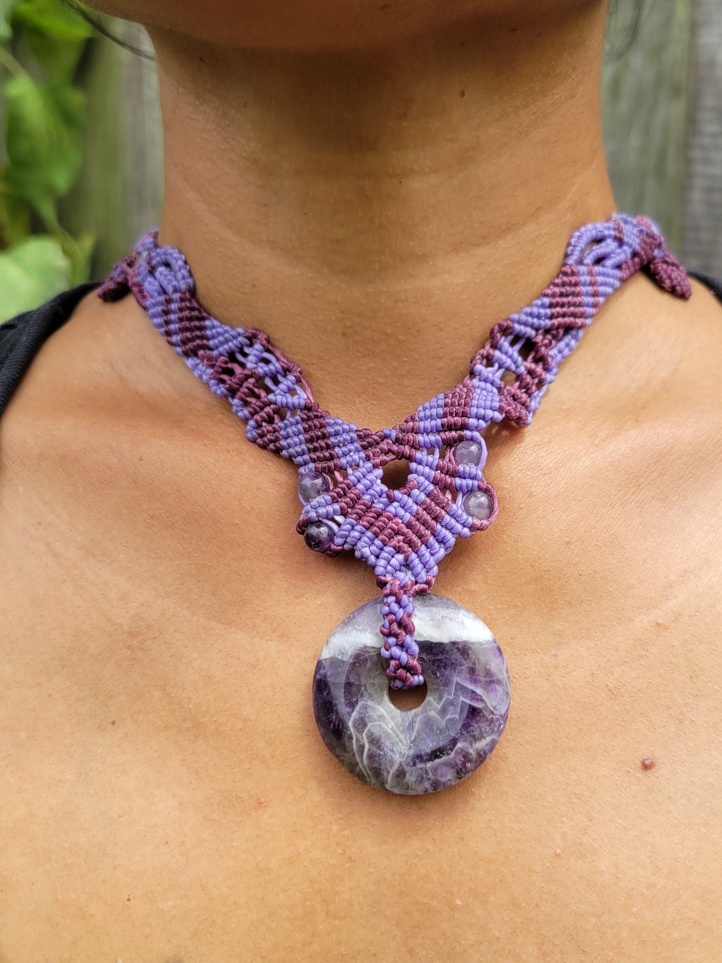 Close-up of a purple woven hair tie on a person's back with a natural background.