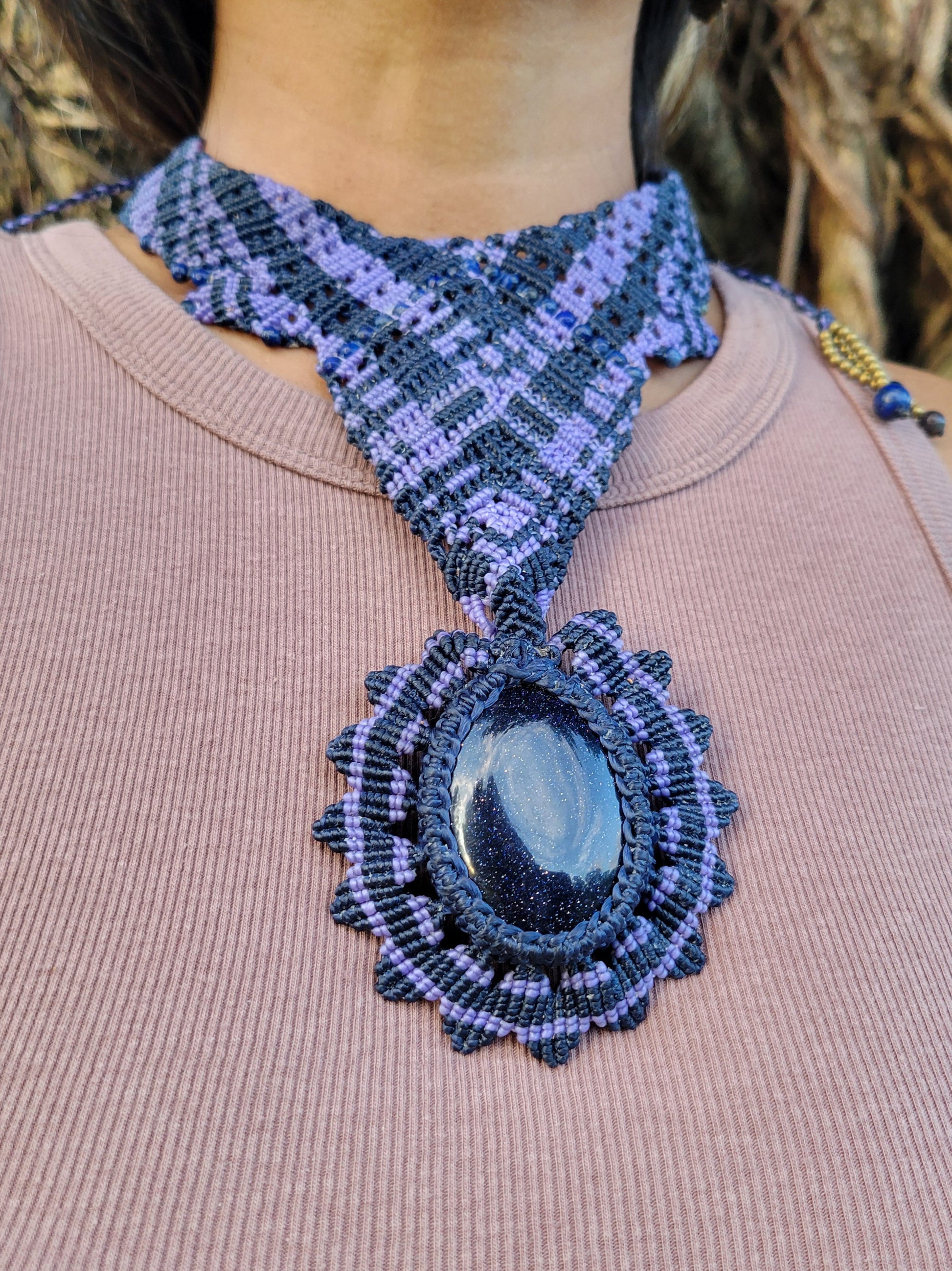 Handmade Boho Necklace featuring oval blue sandstone cabochon and intricate macramé knotwork in purple tones.
