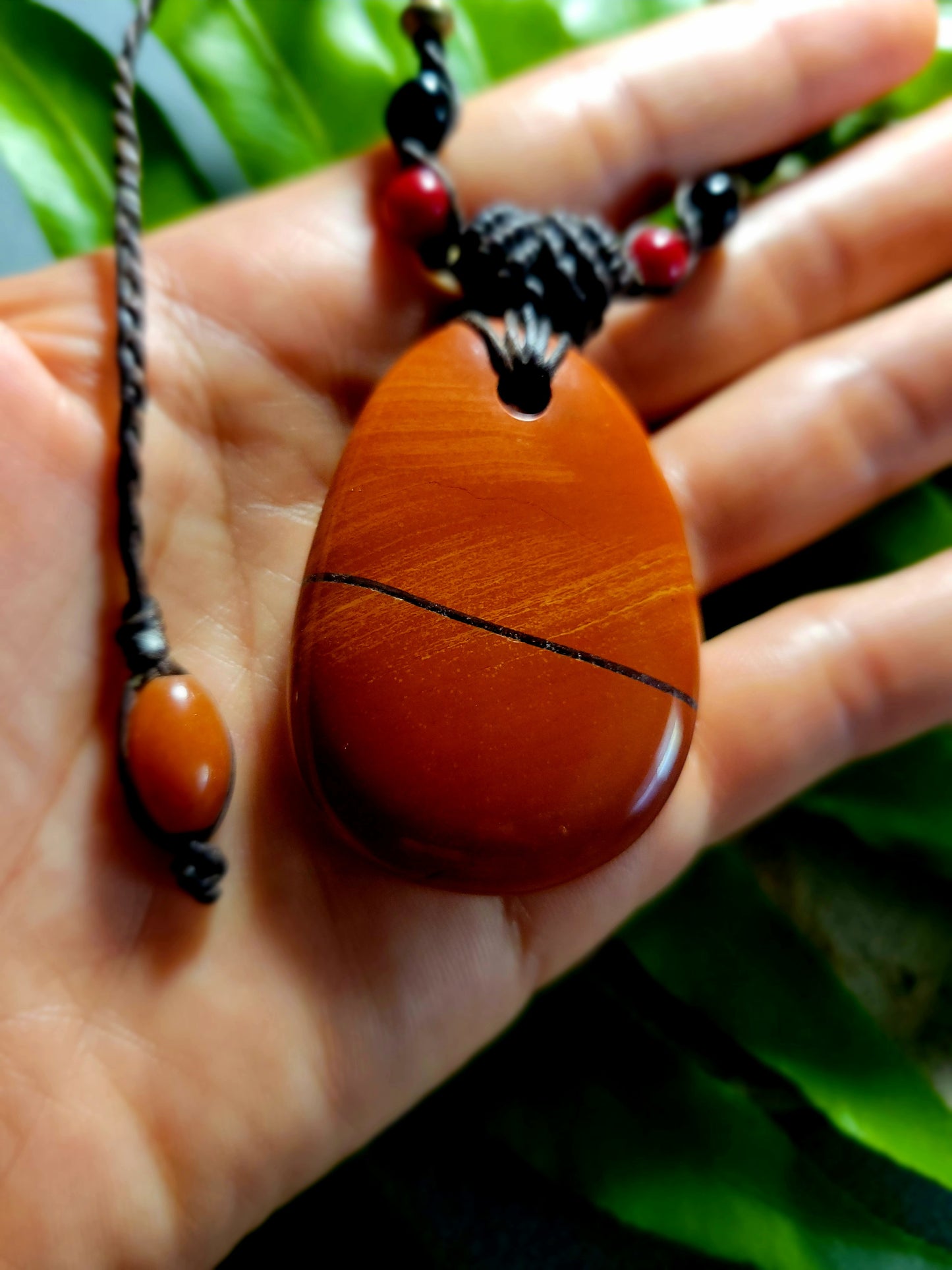 Jasper Healing Stone pendant held in hand, featuring natural red jasper design and boho style necklace.
